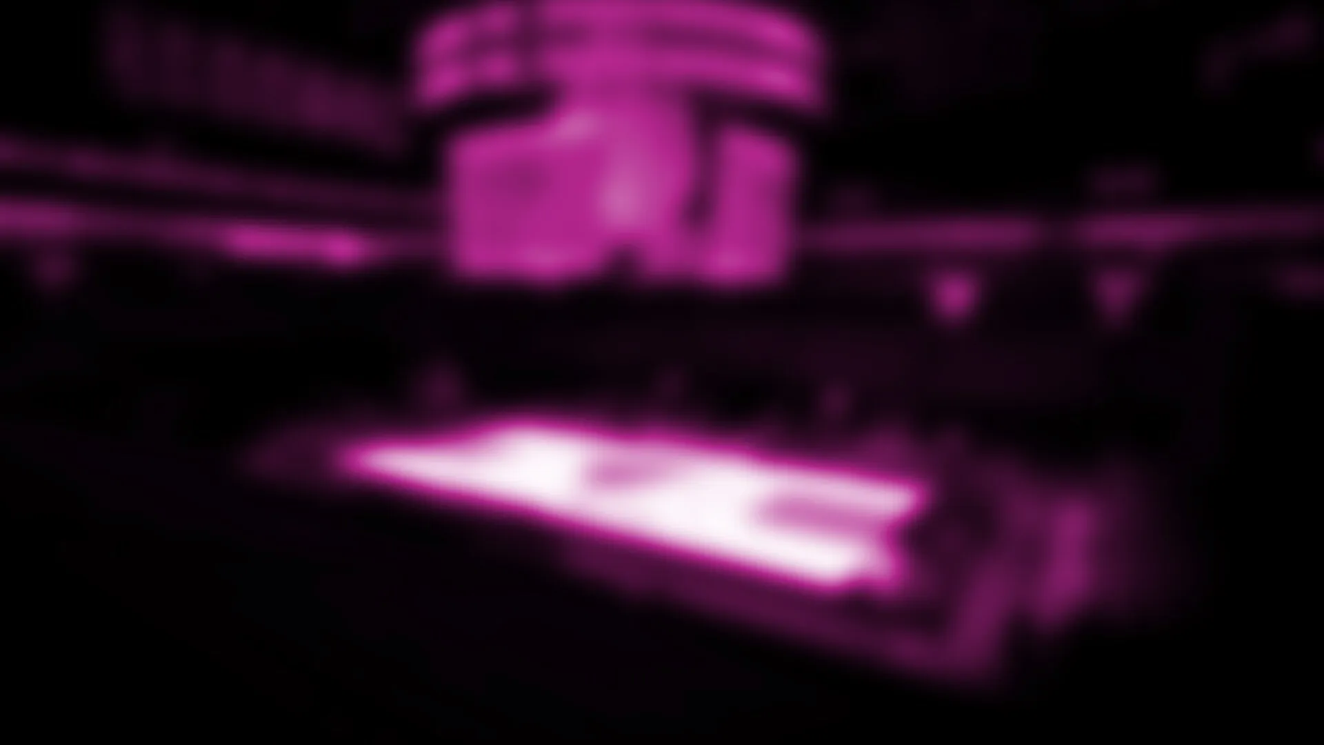 Una vista borrosa de un pabellón de baloncesto con luz rosa, con una cancha muy iluminada en el centro y el marcador encima.