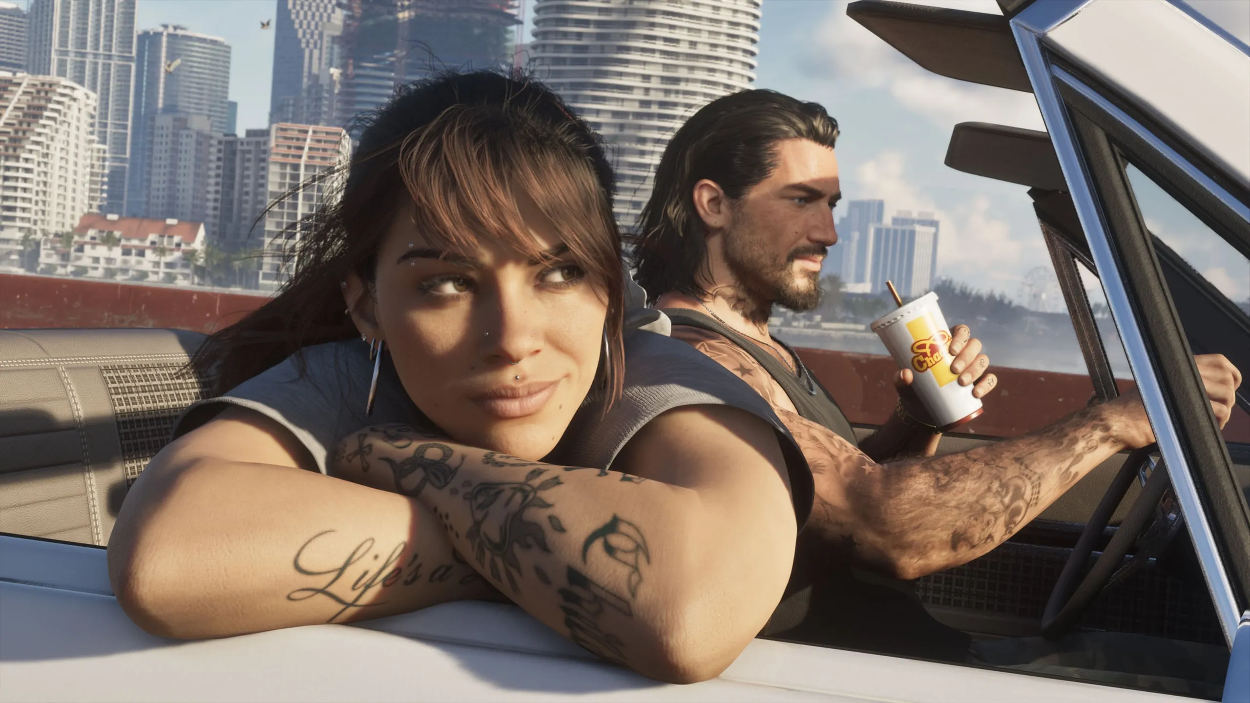 Lucia leans on the door of a convertible and smiles, while Jason drives with a soft drink in his hand.