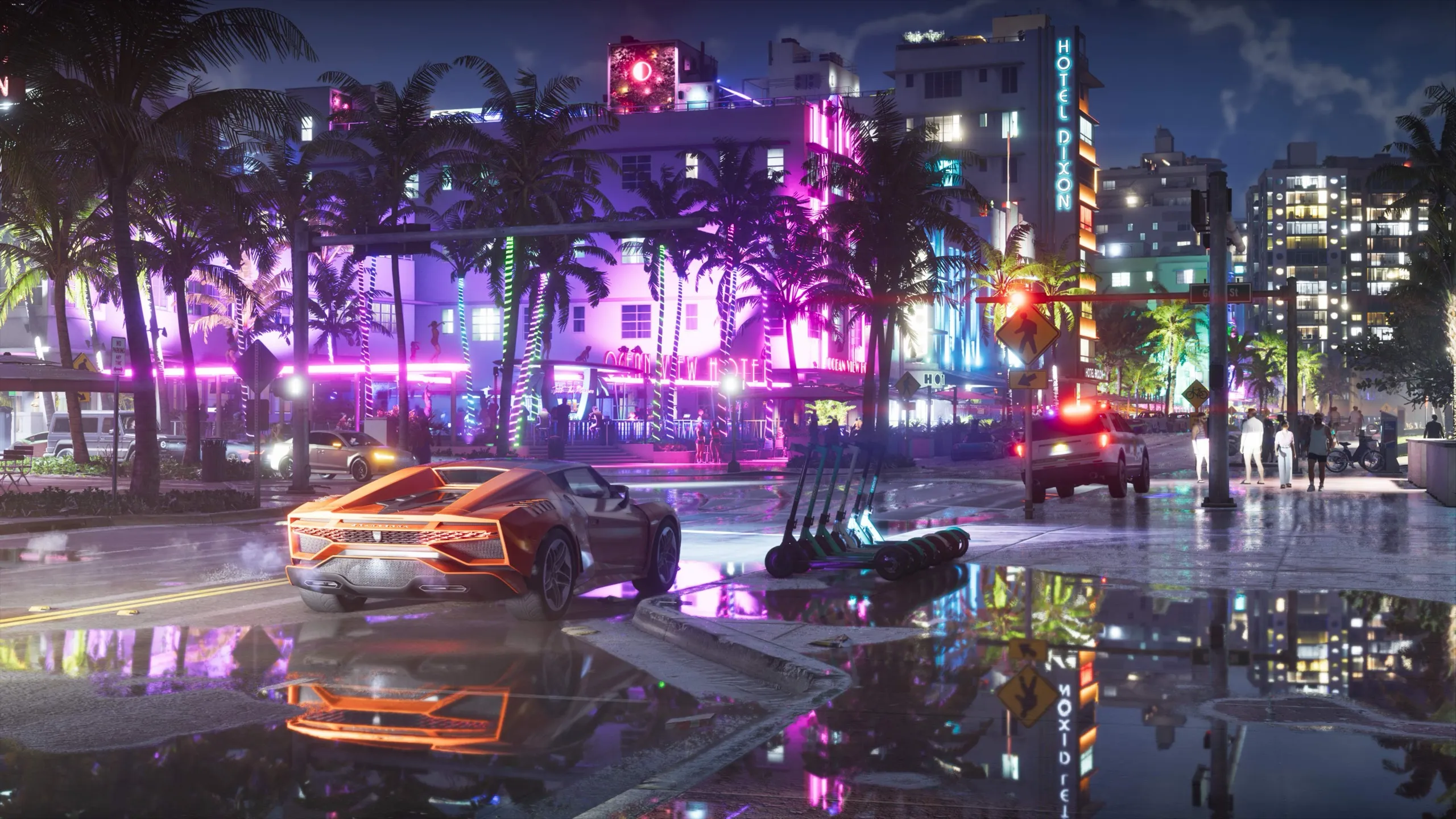 An orange sports car drives along a wet street at night, past palm trees lit in pink and green and the neon sign of the Hotel Dixon, all reflected in the puddles.