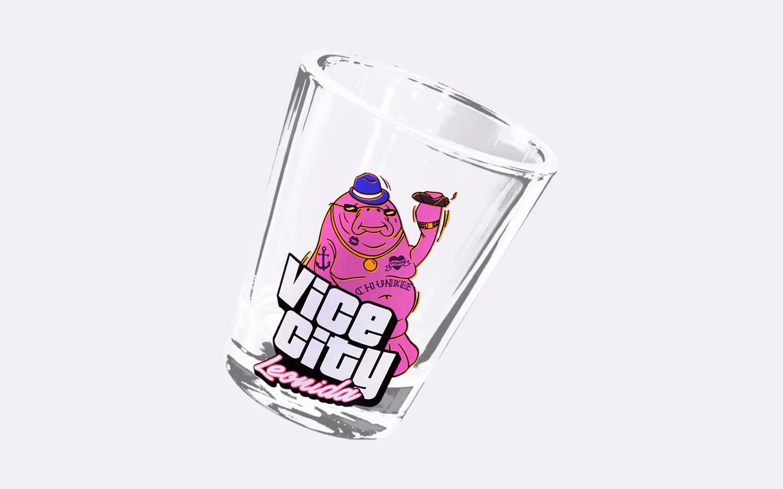 Ein durchsichtiges Schnapsglas mit einer lila Seekuh mit Hut und dem Vice-City-Logo darauf.
